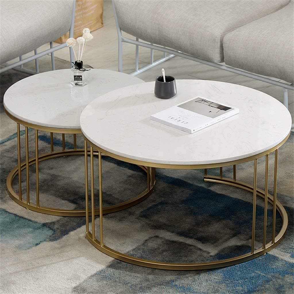 Pair of gold and white round metal coffee tables beside a sofa